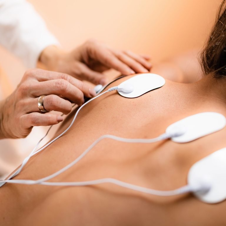 Upper Back Physical Therapy with TENS Electrode Pads, Transcutaneous Electrical Nerve Stimulation. Therapist Positioning Electrodes onto Patient's Upper Back