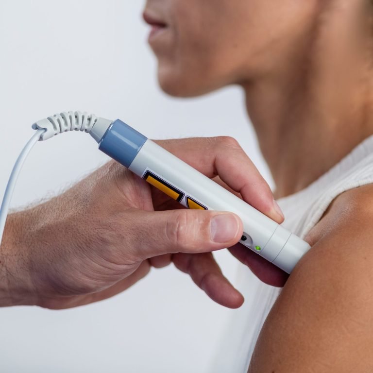 A physical therapist performs laser therapy on a patients shoulder to reduce pain, decrease inflammation, and promote tissue healing, aiding in faster recovery and improved mobility
